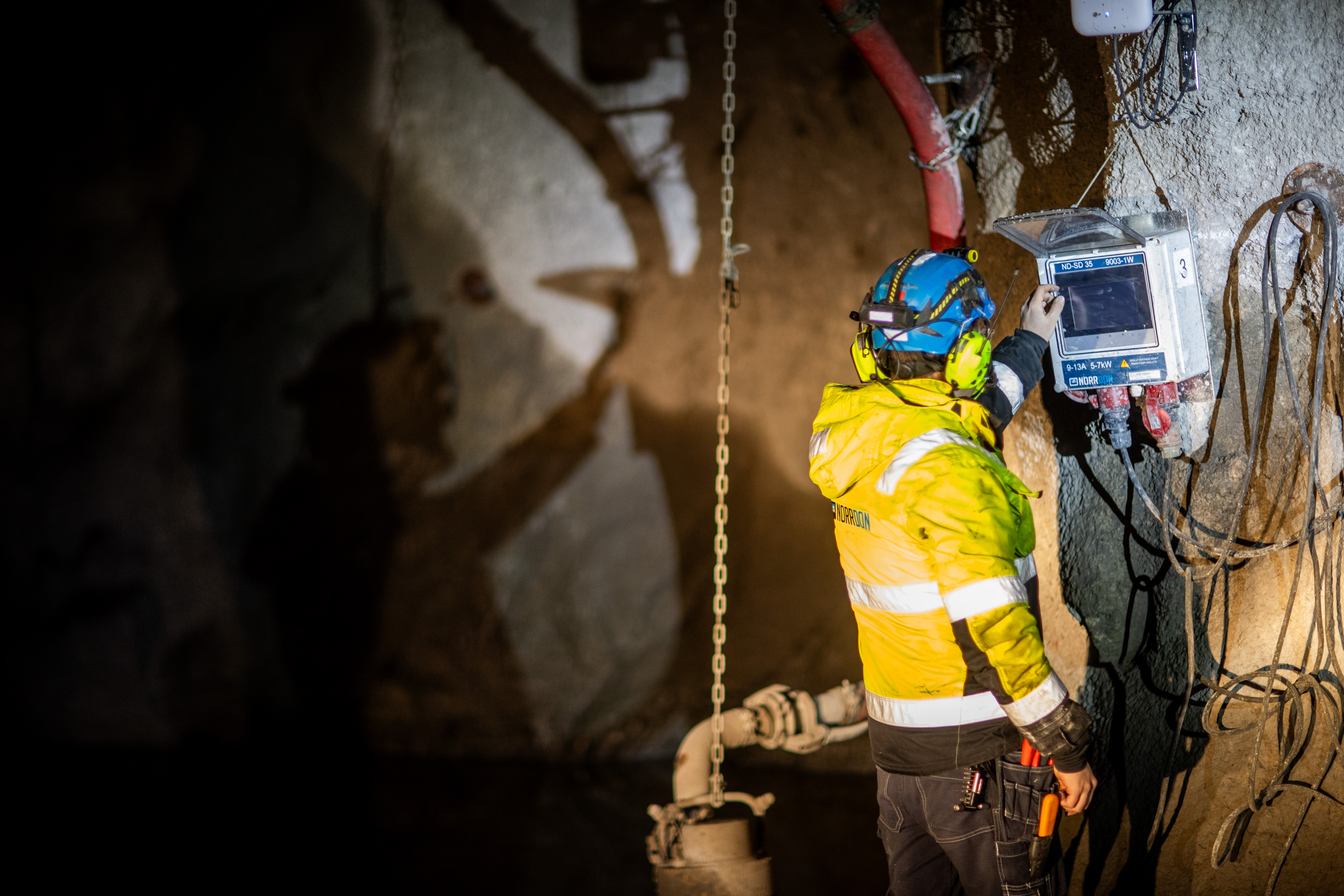 Norr-Don technician operating a wall-mounted Smart Pump Drive controller underground